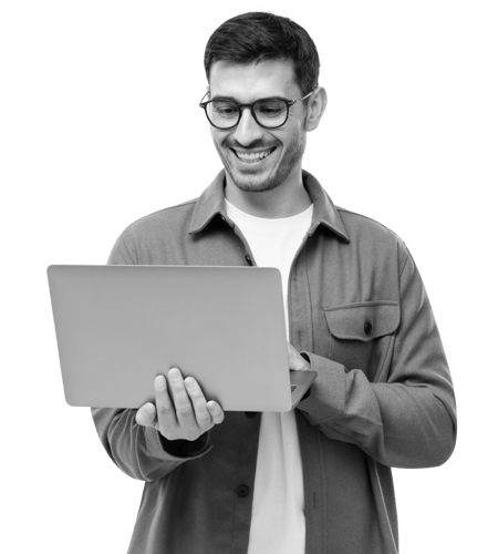 A man with glasses in casual wear. He smiles as he looks down at his laptop.